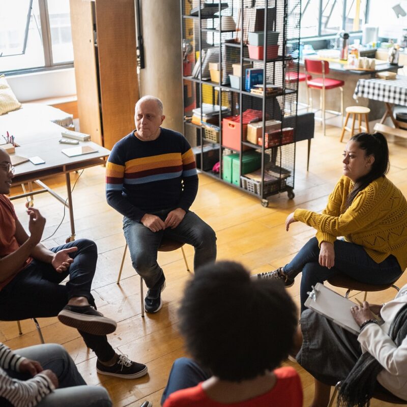 Young man talking in group therapy at a coworking