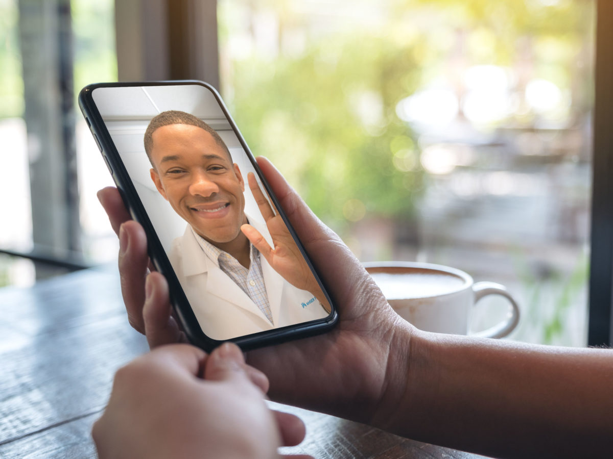 Woman's Hands Holding Black Mobile Phone With Doctor On Screen