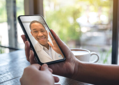 Woman's hands holding black mobile phone with doctor on screen