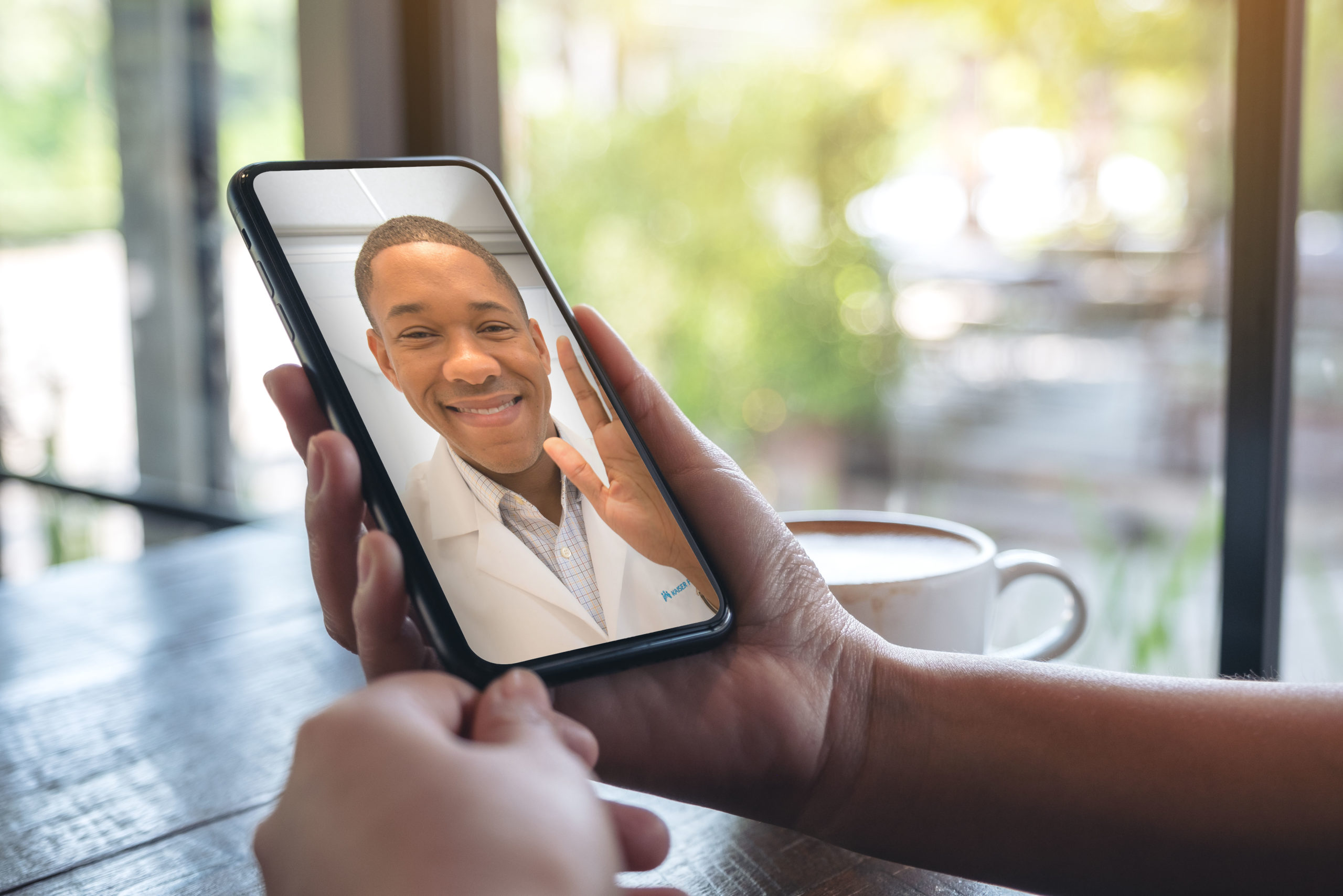 Woman's hands holding black mobile phone with doctor on screen