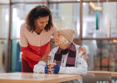 Being thirsty. Pleasant unhoused woman sitting at the table while wanting to drink water