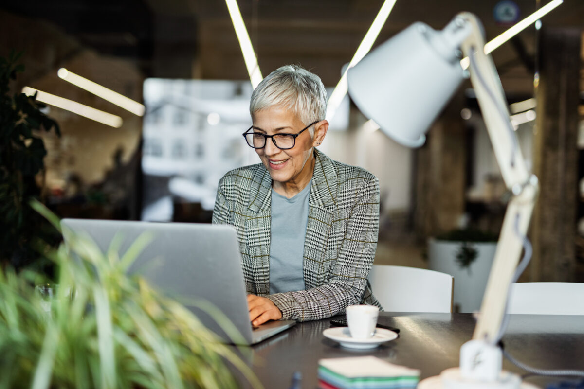 Happy mature entrepreneur working on a computer in the office.