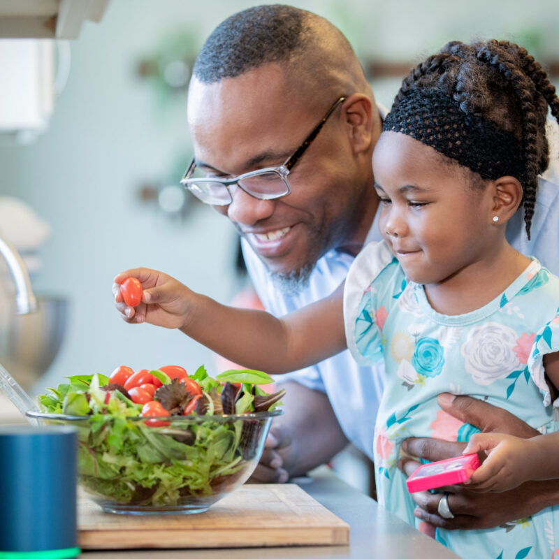 Toddler girl preparing food with father