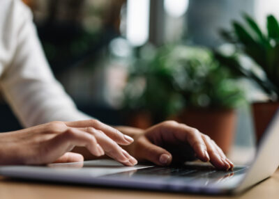 Closeup shot hands using laptop computer and internet, typing on keyboard, searching information. Freelancer copywriter typing text, edit something, working at home