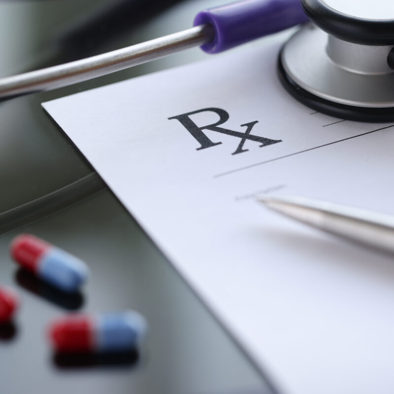 Ballpoint pen lying on medical prescription near phonendoscope in doctors office. Illegal prescription of drugs concept