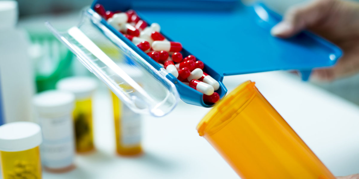 Pill Counter filling Pill Bottle with Capsules A pharmacist fulfilling a prescription