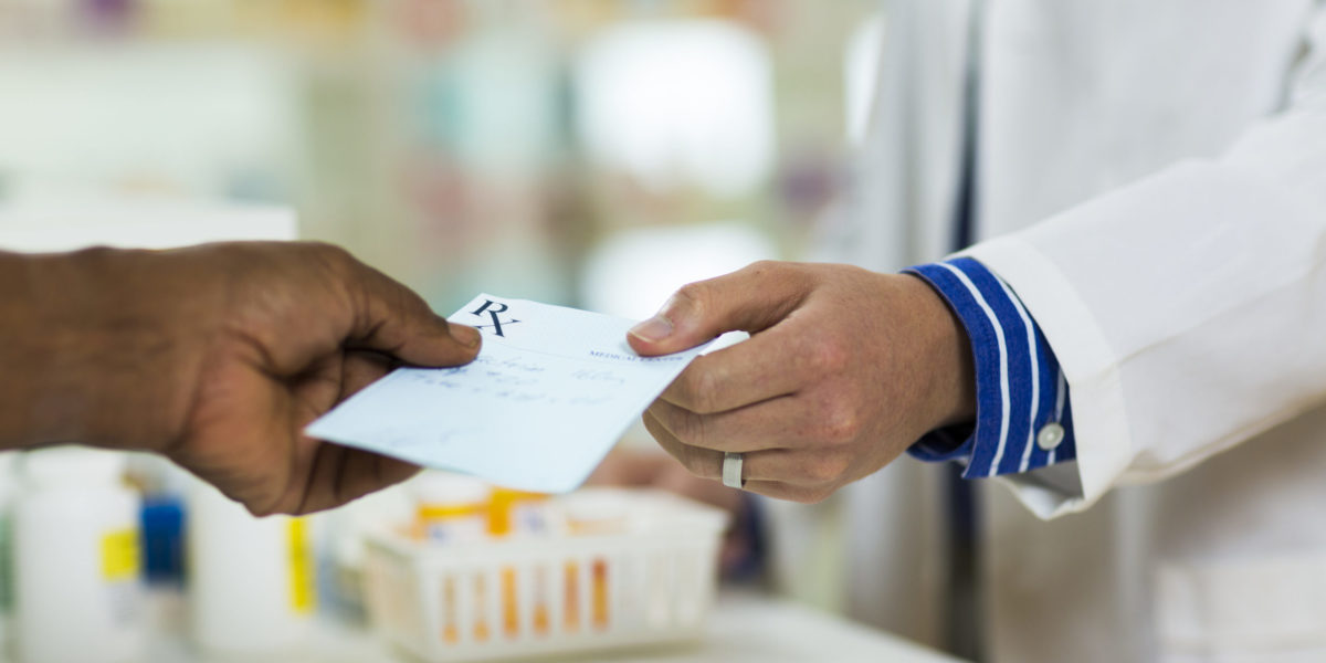 A man handing a prescription to a pharmacists