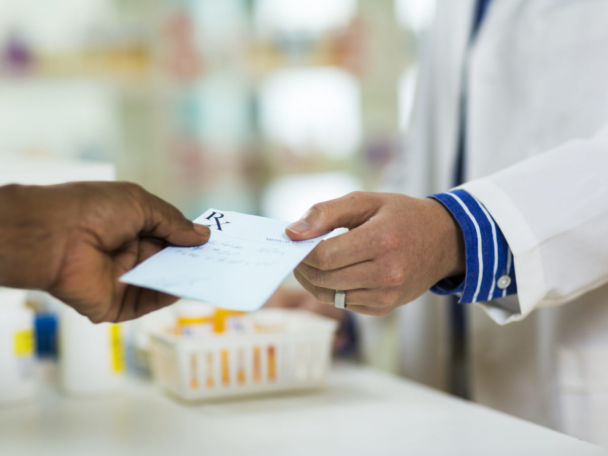 A man handing a prescription to a pharmacists