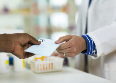 A man handing a prescription to a pharmacists