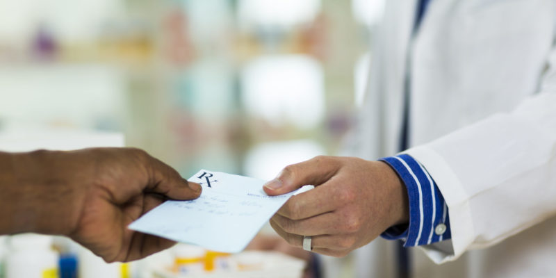 A Man Handing A Prescription To A Pharmacists