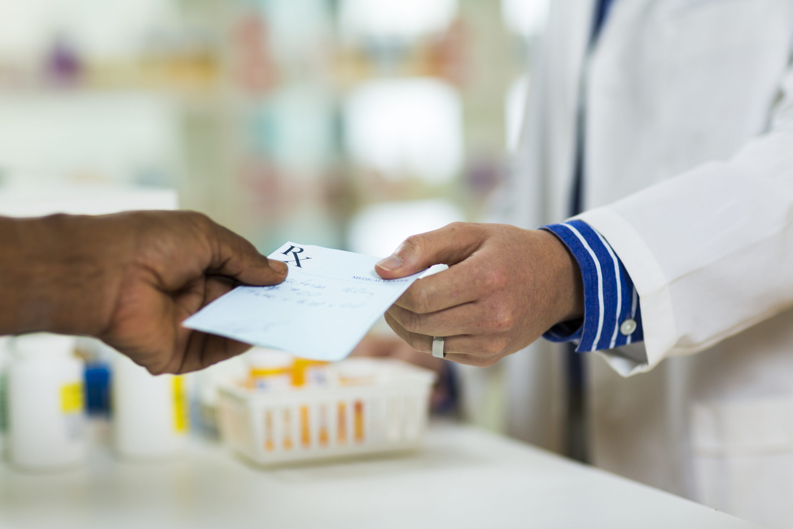 A man handing a prescription to a pharmacists