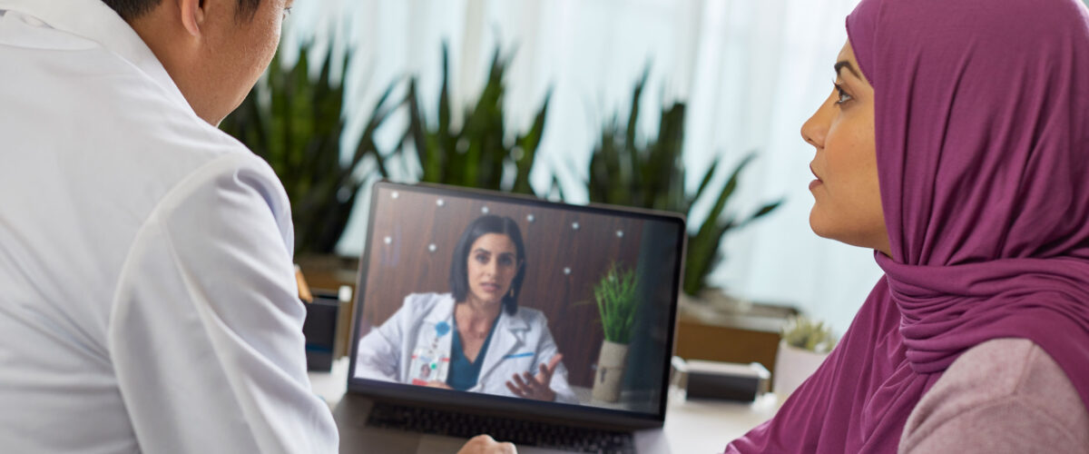 Doctor And Patient Consulting With Another Doctor Via Video Conference