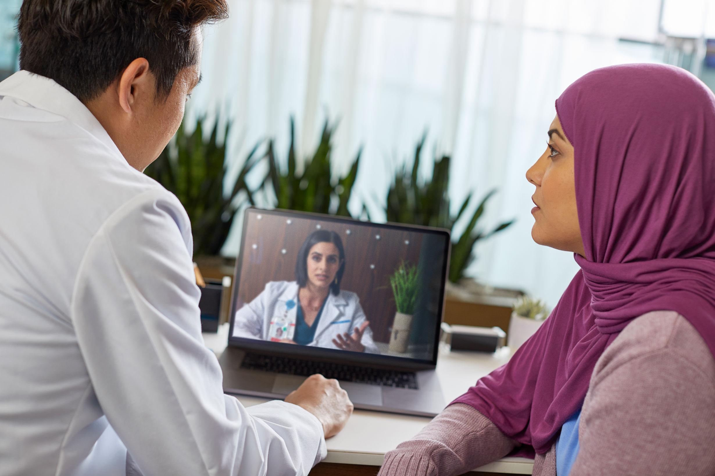 Doctor and patient consulting with another doctor via video conference